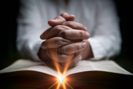 Photo for Faith with holy bible concept. Hands of a female prayer worship God with holy bible on black background in church. Christian woman who believe in Jesus read and study the grace of the holy scriptures. - Royalty Free Image