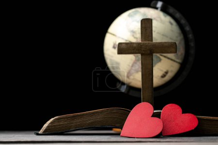 Das rote Herz auf dem heiligen Bibelbuch ist das Symbol der Liebe Gottes. Gott schenkt allen Menschen Liebe. Wir können die Bibel in der Kirche sehen oder finden. Die Bibel ist die christliche Religion. Zwei Herzen auf Seite.