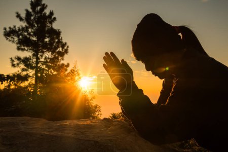 Photo for Woman kneeling to pray on Easter Day. Silhouette of prayer woman kneeling and praying over autumn sunset background. Forgive concept. praying over beautiful sunrise background - Royalty Free Image