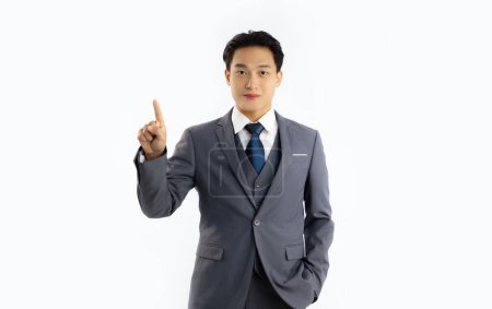 Téléchargez les photos : Jeune homme d'affaires asiatique en costume de couleur grise regardant caméra posant doigt pionting et toucher sur fond blanc. - en image libre de droit