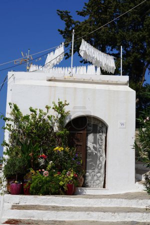 Varias flores, arbustos y árboles en macetas decoran el porche de una casa en el casco antiguo de Lindos, isla de Rodas, Grecia