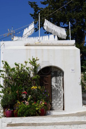 Varias flores, arbustos y árboles en macetas decoran el porche de una casa en el casco antiguo de Lindos, isla de Rodas, Grecia