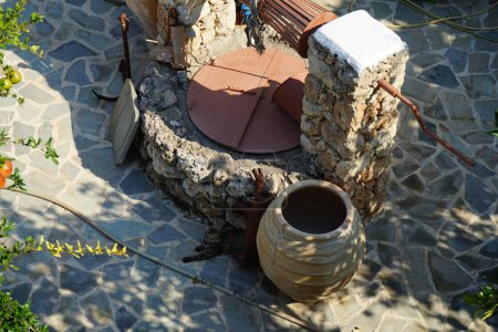 Un viejo pozo de piedra para el agua con un cubo y jarras se encuentra cerca de la Epar. Od. Lardou-Lindou carretera en Lardos, isla de Rodas, región del Egeo Meridional, Grecia 