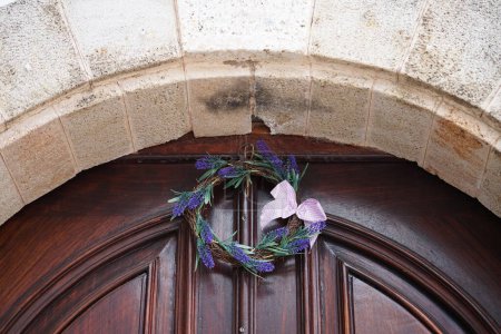 Ein dekorativer Kranz mit künstlichen Lavendelblüten schmückt den Eingang zu einem mittelalterlichen Haus in Lindos. Lindos ist eine archäologische Stätte, ein Fischerdorf. Rhodos, Dodekanes, Griechenland