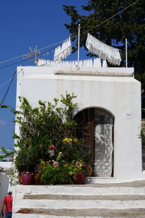 Verschiedene Blumen, Sträucher und Bäume in Töpfen schmücken im August die Veranda eines Hauses im antiken Lindos. Lindos ist eine archäologische Stätte, ein Fischerdorf und eine ehemalige Gemeinde auf Rhodos, Griechenland. 