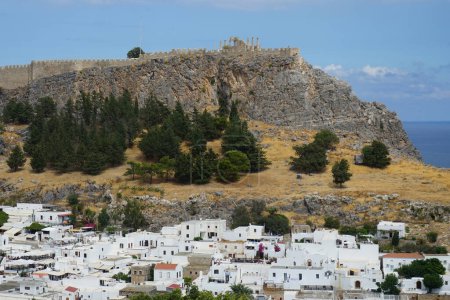 Blick auf die weißen Gebäude der Kapitänshäuser aus dem 16. und 18. Jahrhundert und die antike Akropolis von Lindos im August. Lindos ist eine archäologische Stätte, ein Fischerdorf und eine ehemalige Gemeinde auf Rhodos, Griechenland.                               