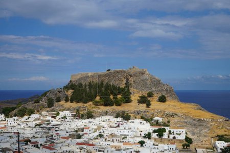 View of the white buildings of Captains houses of the 16th-18th centuries and the ancient Acropolis of Lindos in August. Lindos is an archaeological site, a fishing village. Lindos, Rhodes Island, Dodecanese, Greece 