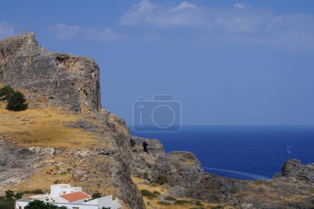 View of the white buildings of Captains houses of the 16th-18th centuries and the ancient Acropolis of Lindos in August. Lindos is an archaeological site, a fishing village. Lindos, Rhodes Island, Dodecanese, Greece  