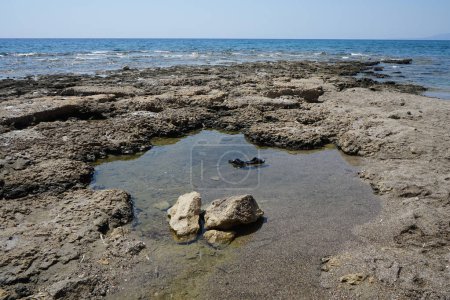 Foto de Las chanclas de goma flotan en el agua de mar después de la marea baja en la costa mediterránea de Pefki. Pefkos o Pefki es un conocido balneario situado en la costa oriental de la isla de Rodas. Pefkos o Pefki, isla de Rodas, Grecia - Imagen libre de derechos
