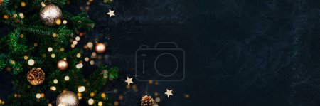 Banner with Christmas tree branches, golden baubles and pine cones on black background with Christmas bokeh lights. New Year concept. Top view, copy space.
