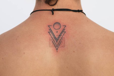 Téléchargez les photos : Détail du tatouage récent terminé avec l'irritation de la peau rouge, design minimaliste avec des points triangles et des cercles - en image libre de droit