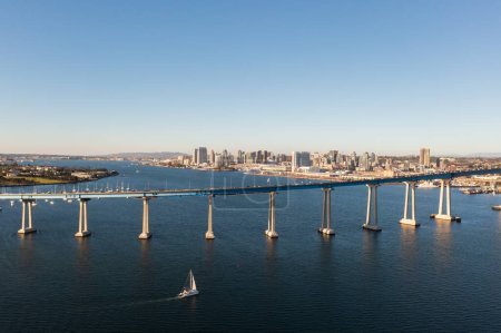 Coronado bridge with San Diego skyline in distance, sail boat in foreground. 