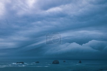 Storm clouds from bomb cyclone over sea stacks in the ocean at the Oregon Coast. 
