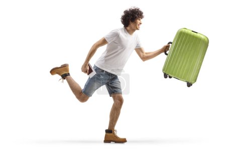 Photo for Full length profile shot of a young casual man running with a suitcase isolated on white background - Royalty Free Image