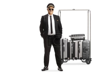 Photo for Mature man in a uniform in front of suitcases on a cart isolated on white background - Royalty Free Image