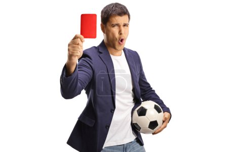 Foto de Joven casual sosteniendo un balón de fútbol y mostrando una tarjeta roja aislada sobre fondo blanco - Imagen libre de derechos