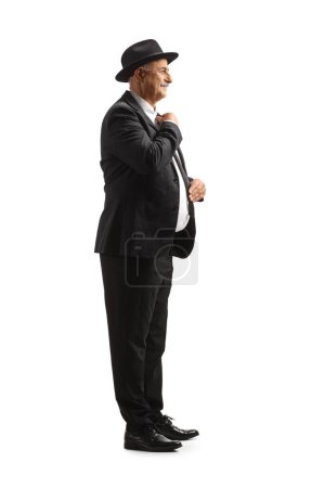 Téléchargez les photos : Plan de profil complet d'un homme mature élégant se préparant et triant ses vêtements isolés sur fond blanc - en image libre de droit