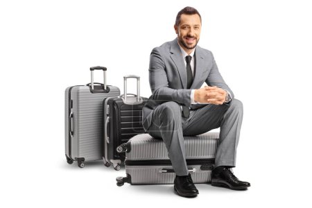 Photo for Bussinessman sitting on a suitcase and smiling isolated on white background - Royalty Free Image