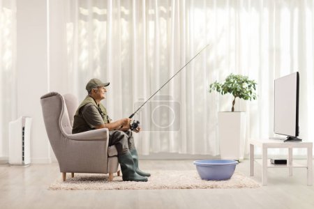 Photo for Fisherman fishing in a washing bowl in front of tv at home - Royalty Free Image