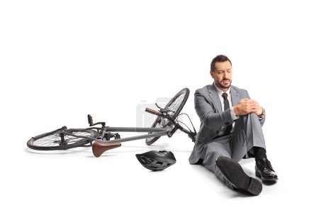 Téléchargez les photos : Homme d'affaires tombant d'un vélo et tenant son genou isolé sur fond blanc - en image libre de droit