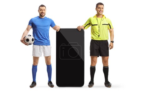Foto de Retrato completo de un jugador de fútbol y un árbitro parado junto a un gran smartphone aislado sobre fondo blanco - Imagen libre de derechos