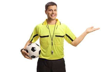 Foto de Smiling árbitro de fútbol mostrando con la mano y sosteniendo una pelota aislada sobre fondo blanco - Imagen libre de derechos