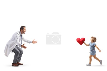 Foto de Foto de perfil completo de una niña corriendo hacia un médico con un corazón rojo en los brazos aislado sobre fondo blanco - Imagen libre de derechos