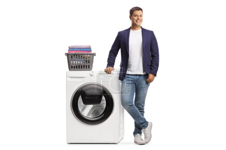 Photo for Young man leaning on a washing machine and smiling isolated on white background - Royalty Free Image
