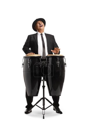 Téléchargez les photos : Gai mature l'homme jouer conga tambours et chant isolé sur fond blanc - en image libre de droit