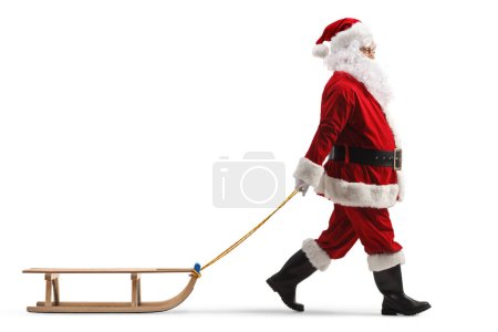 Photo for Full length profile shot of santa claus pulling a wooden sleigh isolated on white background - Royalty Free Image