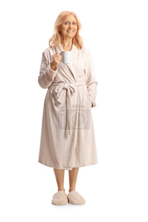 Photo for Full length portrait of a mature woman in a bathrobe holding a cup isolated on white background - Royalty Free Image