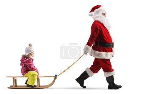Photo for Full length profile shot of santa claus pulling a child on a wooden sleigh isolated on white background - Royalty Free Image