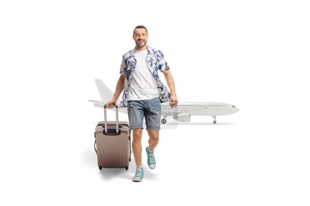 Foto de Retrato completo de un hombre sonriente viniendo de un avión y tirando de una maleta aislada sobre fondo blanco - Imagen libre de derechos