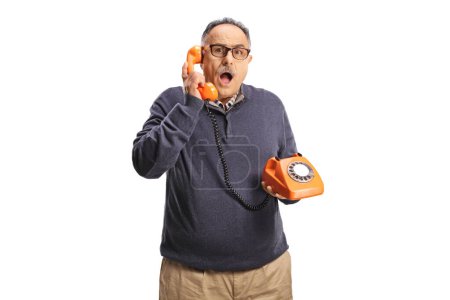 Photo for Shocked mature man using a vintage rotary phone and looking at camera isolated on white backgroun - Royalty Free Image