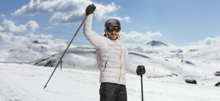 Foto de Hombre con esquís levantando un bastón de esquí en una montaña - Imagen libre de derechos