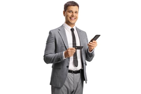 Téléchargez les photos : Jeune homme professionnel utilisant un smartphone et une carte de crédit isolé sur fond blanc - en image libre de droit