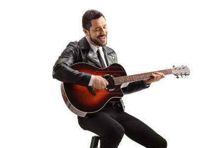 Téléchargez les photos : Musicien masculin jouant une guitare acoustique posée sur une chaise isolée sur fond blanc - en image libre de droit