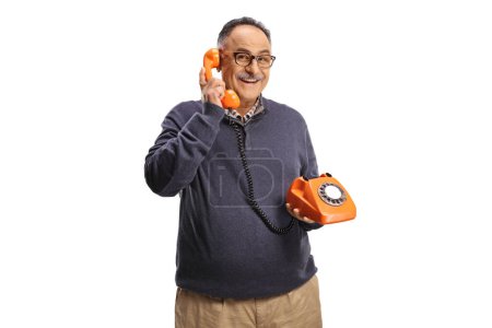 Photo for Cheerful mature man using a vintage rotary phone and looking at camera isolated on white background - Royalty Free Image