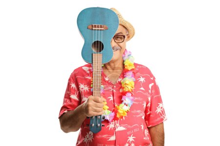 Téléchargez les photos : Homme souriant caché derrière un instrument ukulélé isolé sur fond blanc - en image libre de droit