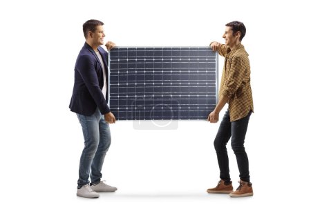 Photo for Full length profile shot of two young men carrying a solar panel isolated on white background - Royalty Free Image