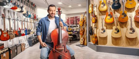 Photo for Man with a cello sitting inside a shop for music instruments - Royalty Free Image