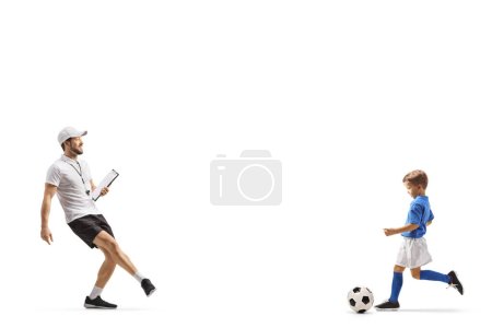 Téléchargez les photos : Entraîneur de football pratiquant coup de pied de ballon avec un garçon isolé sur fond blanc - en image libre de droit
