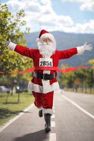 Foto de Feliz Santa Claus terminando primero una carrera en un camino de asfalto en la ciudad - Imagen libre de derechos