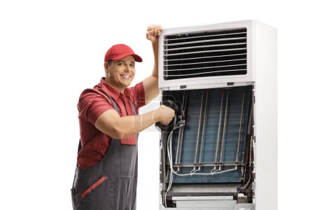 Photo for Worker repairing a self standing portable air conditioning unit isolated on white background - Royalty Free Image