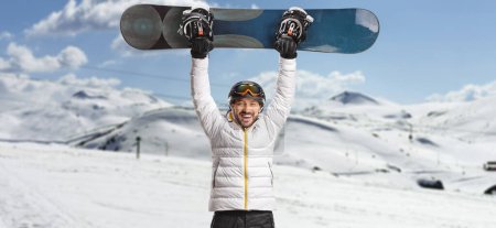 Foto de Hombre levantando una tabla de snowboard en una montaña - Imagen libre de derechos