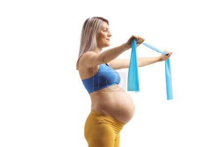 Foto de Perfil de una mujer embarazada haciendo ejercicio con una banda de estiramiento aislada sobre fondo blanco - Imagen libre de derechos