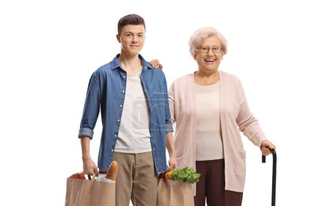 Téléchargez les photos : Jeune homme aidant une femme âgée avec des sacs d'épicerie isolés sur fond blanc - en image libre de droit