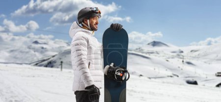 Foto de Perfil de un hombre de pie con una tabla de snowboard en una montaña - Imagen libre de derechos