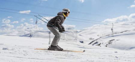 Photo for Full length profile shot of a man skiing in a ski resort - Royalty Free Image
