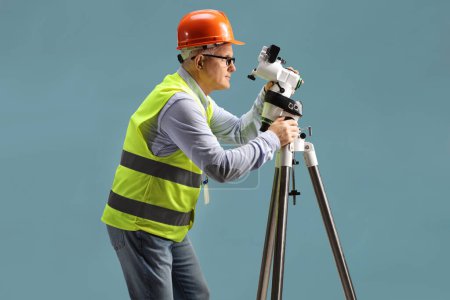Photo for Geodetic surveyor with a measuring equipment isolated on blue background - Royalty Free Image